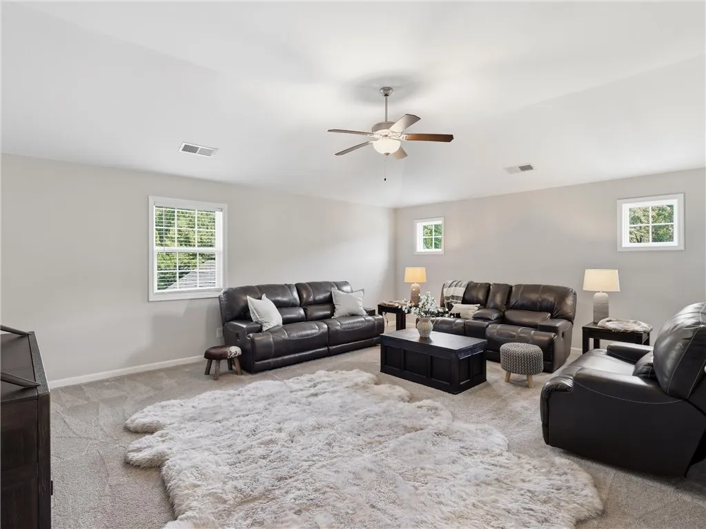 An inviting family room awaits with soft carpet flooring and a comforting ceiling fan.