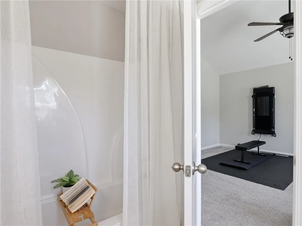 An inviting bathroom space features a tub and shower, with a view into a carpeted room beyond.