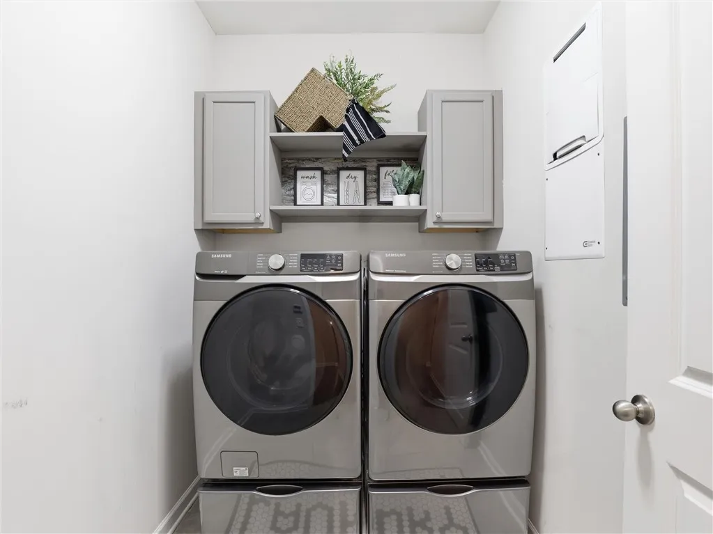 A well-organized laundry area offers a stacked washer and dryer, complemented by smart cabinetry.