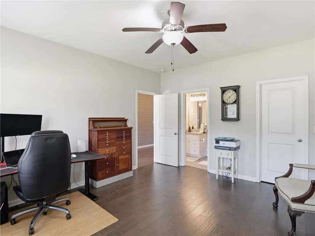 Well-lit room featuring rich wood flooring and a stylish ceiling fan with light.
