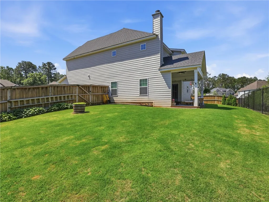 A generous lawn and privacy fencing create an ideal backdrop for outdoor living with a covered patio.