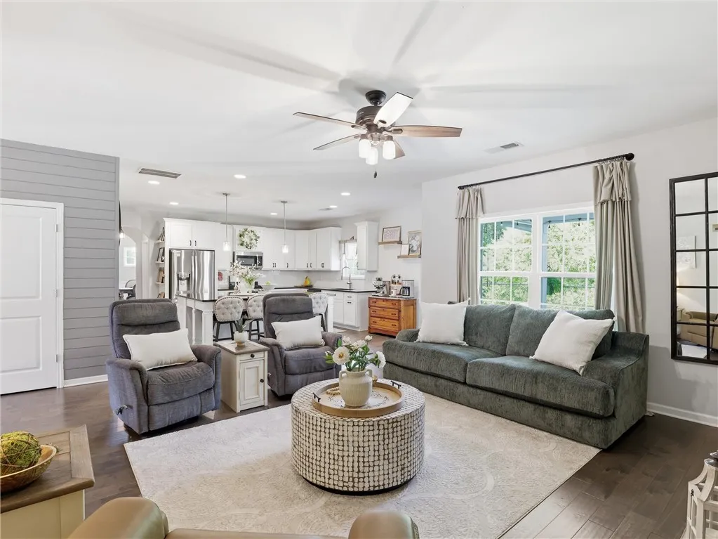An open concept floorplan features dark hardwood flooring and a functional kitchen with stainless steel appliances.
