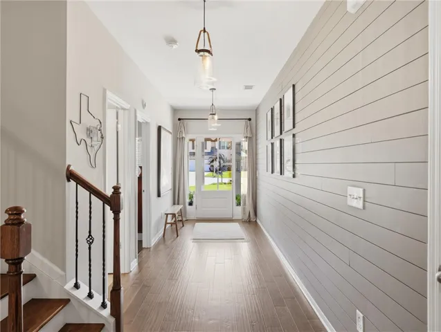 Enter into a bright, welcoming foyer featuring rich hardwood floors and unique wall paneling.