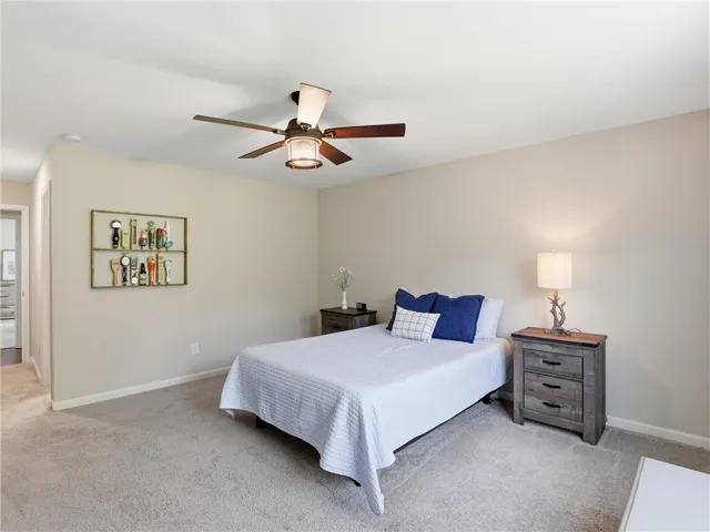 Plush carpeting and a classic ceiling fan create a serene and comfortable bedroom retreat.