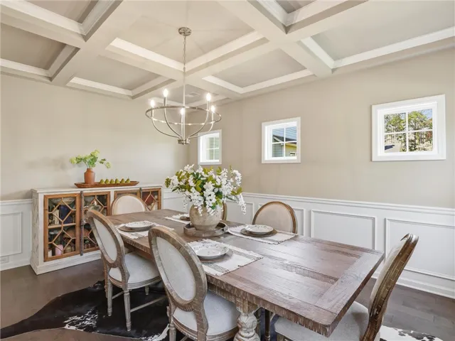 A well-lit dining area features coffered ceilings, hardwood flooring, and elegant wainscoting.