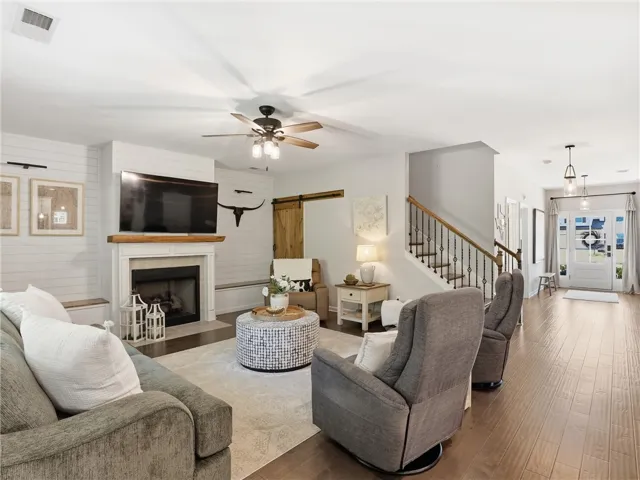 A welcoming living room featuring a cozy fireplace and rich hardwood flooring, flowing into a bright entryway.