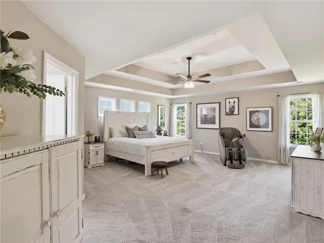A spacious sleeping quarter features a tray ceiling with a fan and numerous windows for abundant natural light.