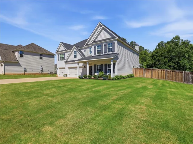 A classic gray siding residence with an inviting covered porch and neatly manicured lawn.