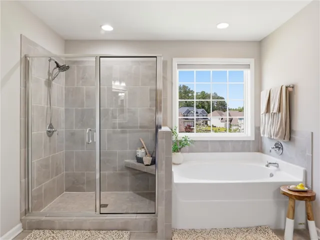 A well-appointed bath features a tiled walk-in shower and a garden tub beneath a bright window.