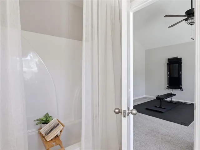An inviting bathroom space features a tub and shower, with a view into a carpeted room beyond.