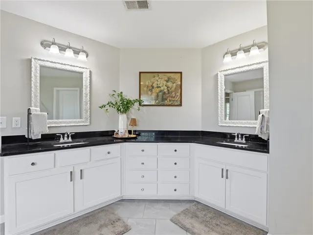 A thoughtfully arranged bathroom featuring dual vanities, each crowned with reflective mirrors, and sleek countertops.