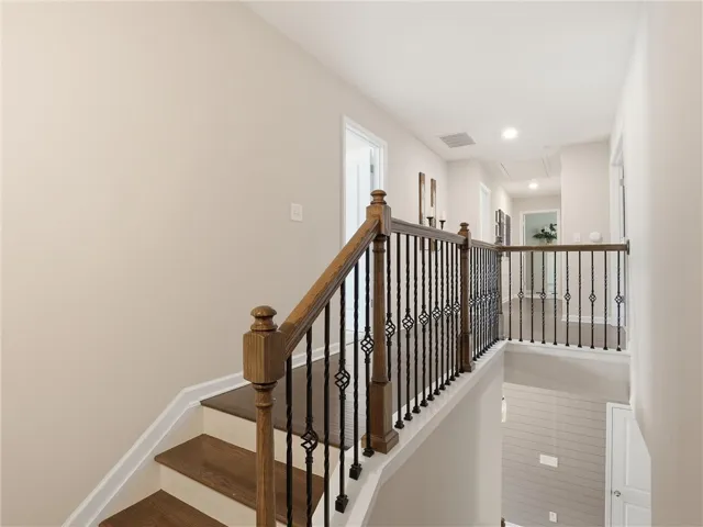 Elegant hardwood stairs and iron balusters lead to a naturally illuminated upper hallway.