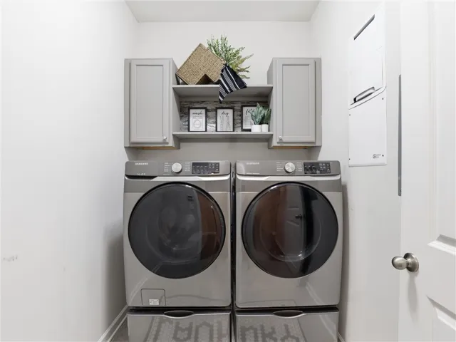 A well-organized laundry area offers a stacked washer and dryer, complemented by smart cabinetry.
