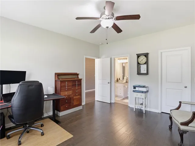Well-lit room featuring rich wood flooring and a stylish ceiling fan with light.