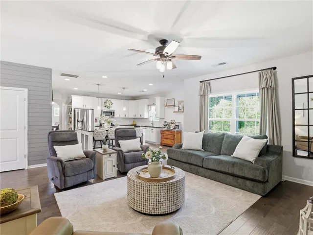 An open concept floorplan features dark hardwood flooring and a functional kitchen with stainless steel appliances.