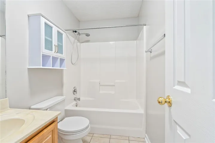 A well-appointed bathroom with tile flooring features a bathtub-shower combination and a practical vanity.
