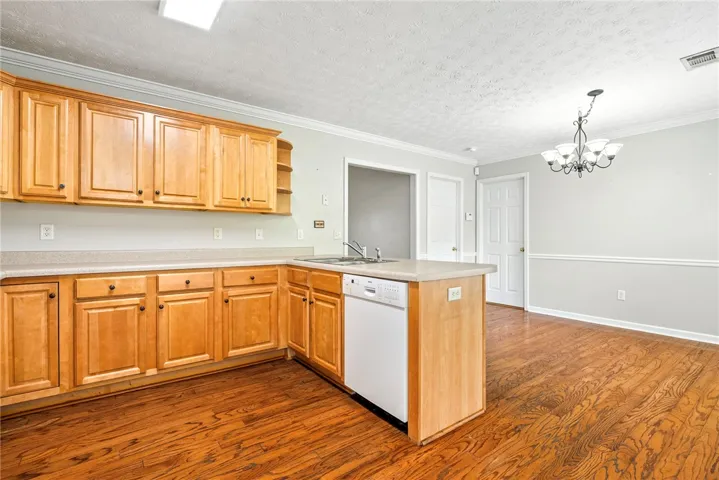 A warm kitchen with hardwood floors transitions to an inviting dining area, ideal for entertaining.