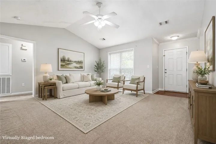 A welcoming living area boasts soaring vaulted ceilings and plush carpeting throughout.