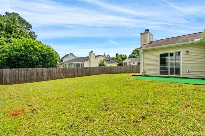 A green lawn provides ample space for outdoor activities, bordered by a wooden privacy fence.