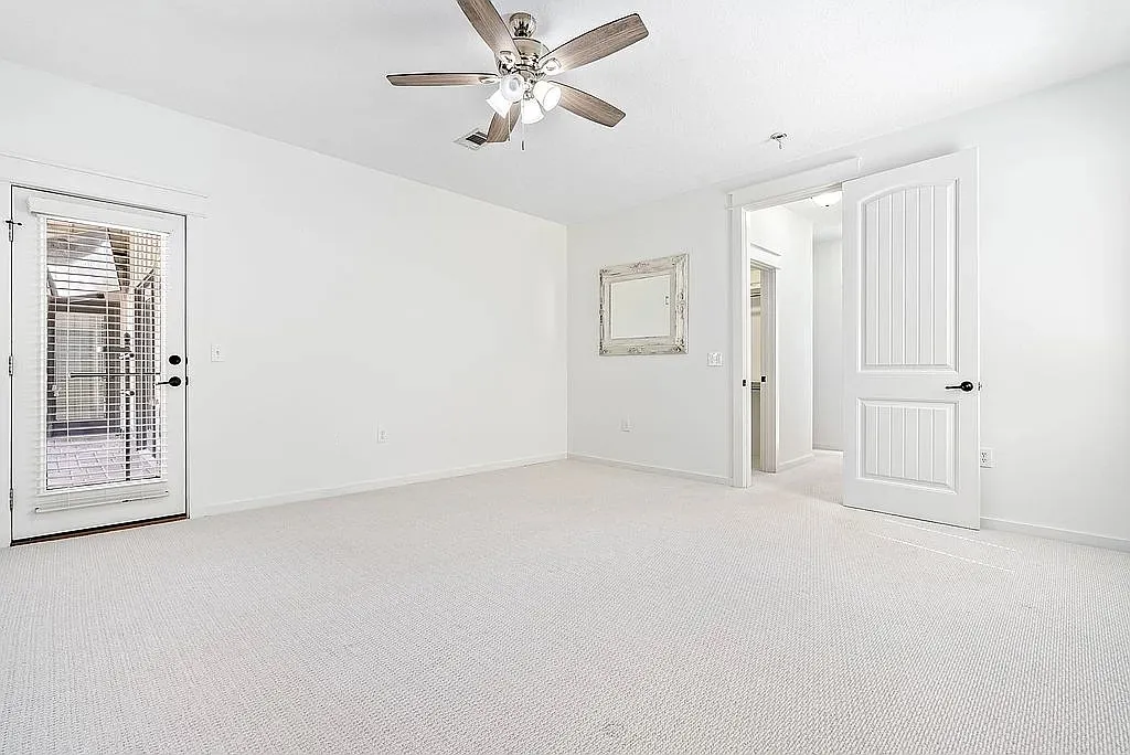 A tranquil bedroom with soft carpet flooring and a glass-paned door leading to the outdoors.