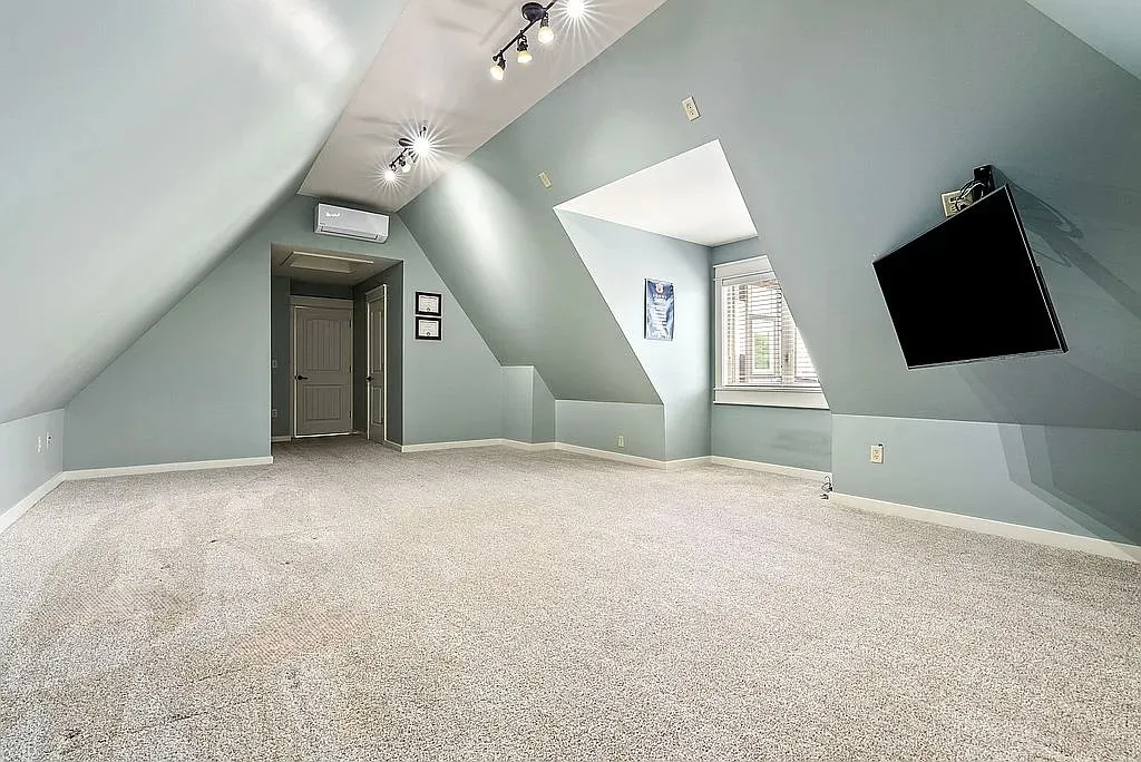A spacious attic retreat features soft carpet and ample lighting, creating a comfortable and versatile living area.