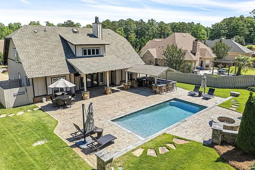 An inviting backyard oasis offers a sparkling pool, generous patio space, and a dedicated outdoor kitchen for al fresco entertaining.