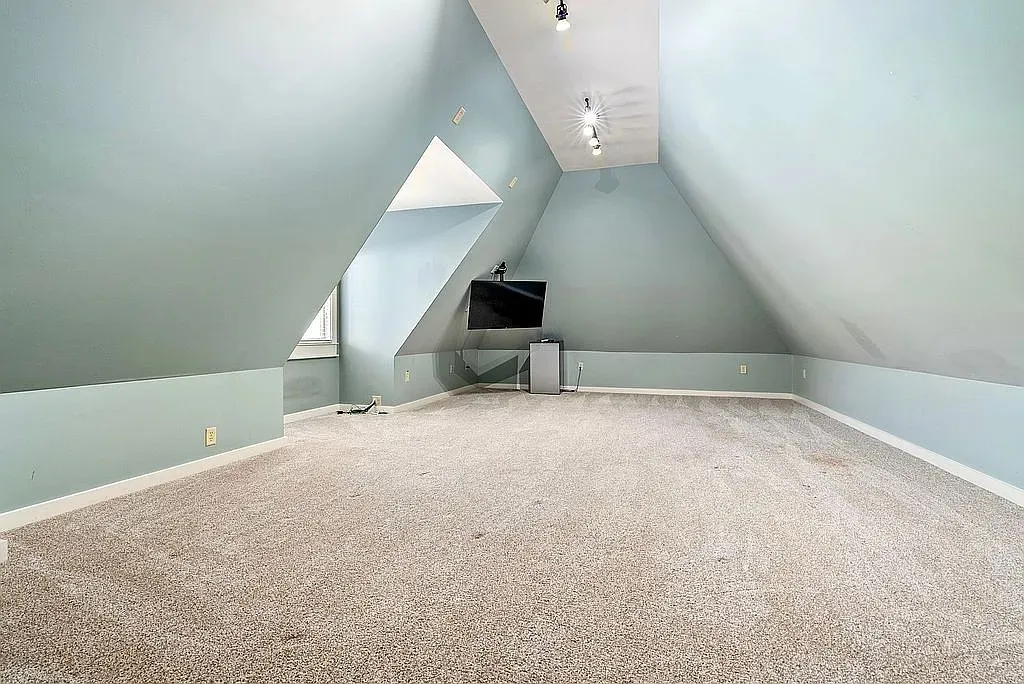 A spacious attic offering versatile living space with sloped walls and warm lighting.