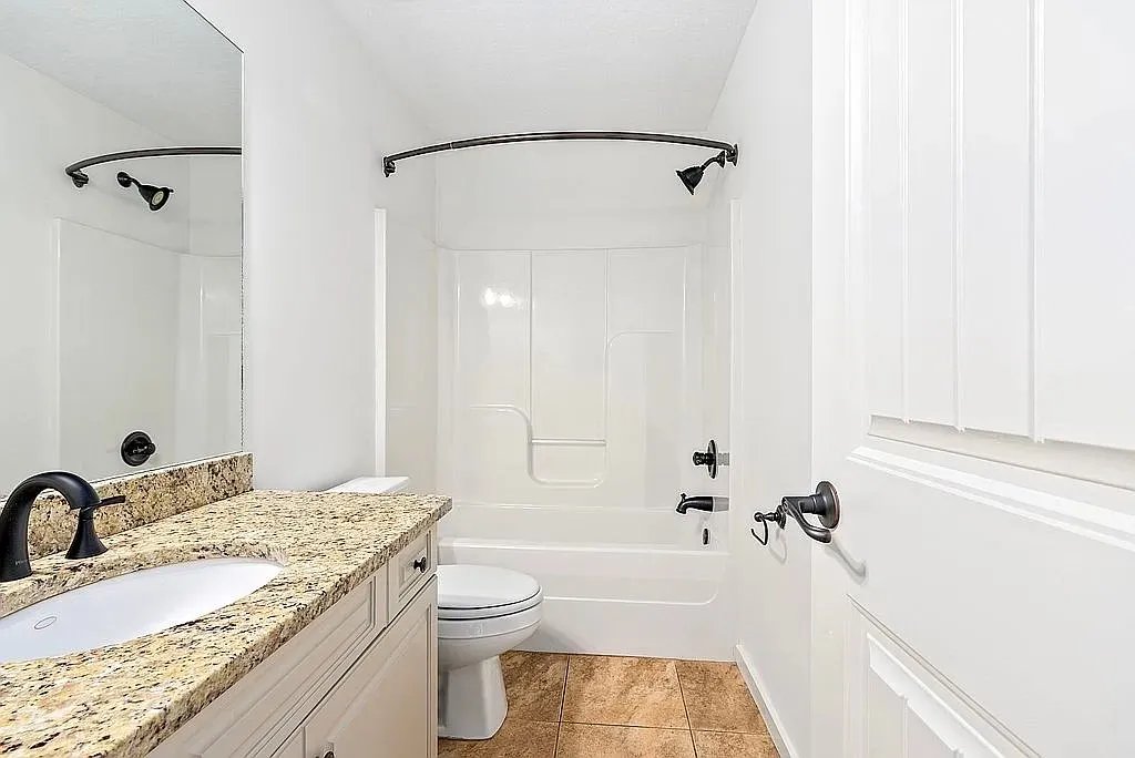 Granite counters and bronze fixtures adorn this tidy, well-appointed bathroom.