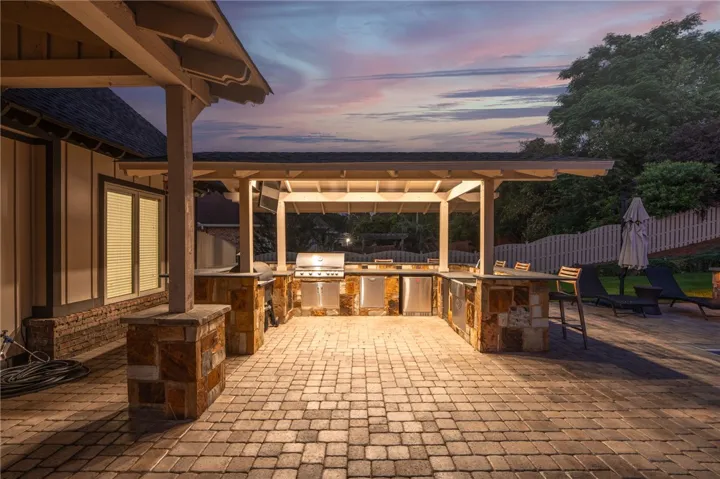 An inviting outdoor kitchen area with a gas grill under a wooden pergola, perfect for al fresco dining.