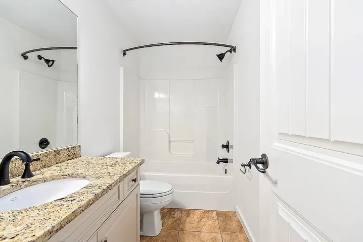Granite counters and bronze fixtures adorn this tidy, well-appointed bathroom.