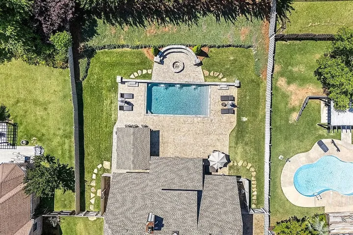 An aerial view reveals two private swimming pools with ample patio space and a built-in fire pit.