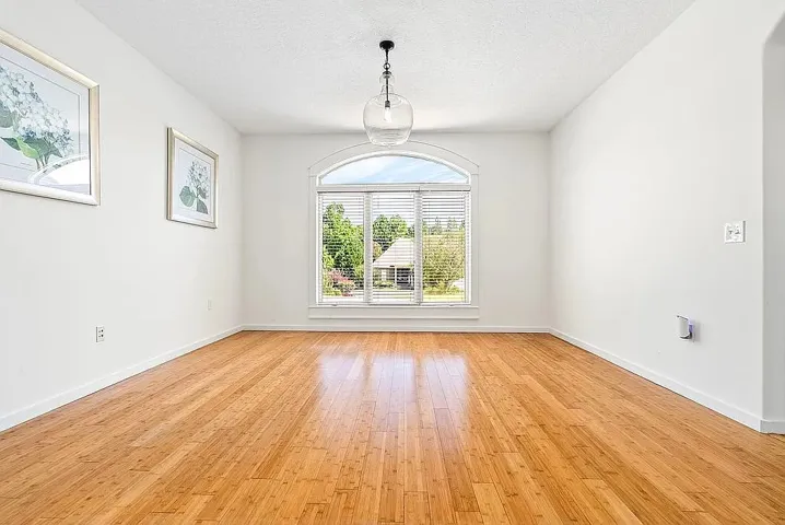 Natural light pours into this room, highlighting the warm wood flooring and tranquil neighborhood views.