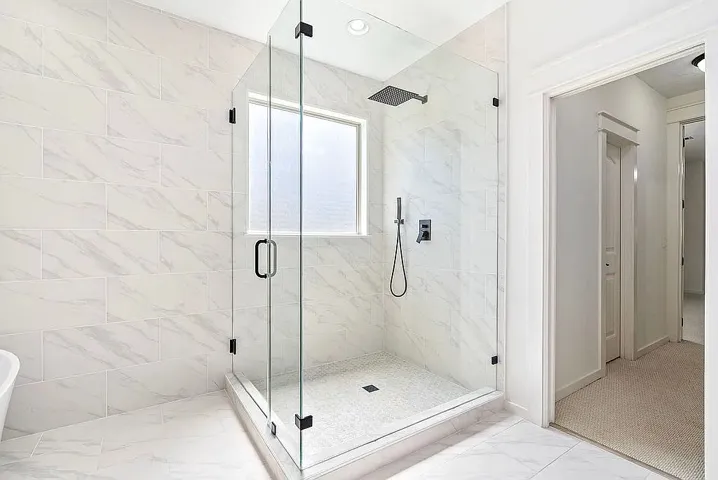A grand, naturally illuminated shower with elegant tile work and modern fixtures.
