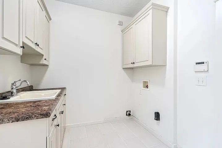A well-appointed laundry space features practical cabinetry and a convenient utility sink for everyday tasks.