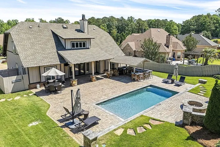 An inviting backyard oasis offers a sparkling pool, generous patio space, and a dedicated outdoor kitchen for al fresco entertaining.