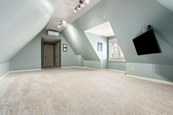 A spacious attic retreat features soft carpet and ample lighting, creating a comfortable and versatile living area.