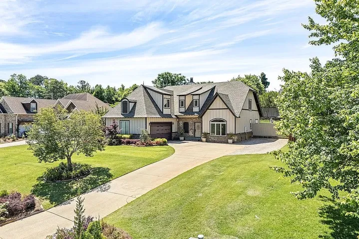 An inviting curved driveway leads to this charming two-story residence, framed by mature trees and manicured lawns.
