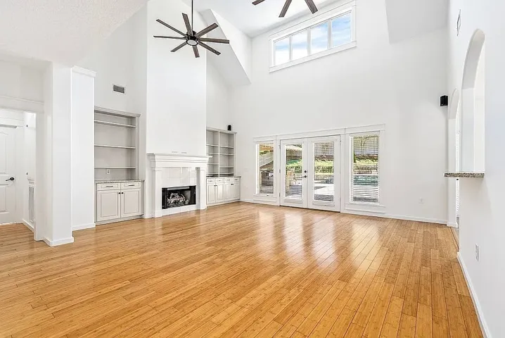 A spacious living room features vaulted ceilings, a cozy fireplace, built-in shelving, and direct outdoor access.