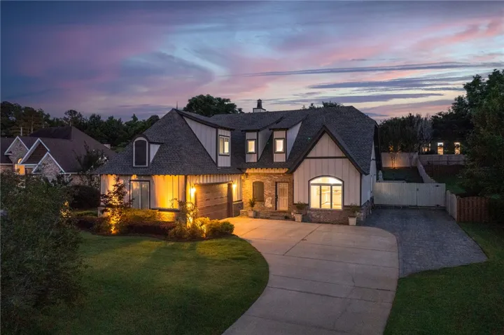 Dramatic sunset hues enhance this charming home's inviting facade and landscaped grounds.
