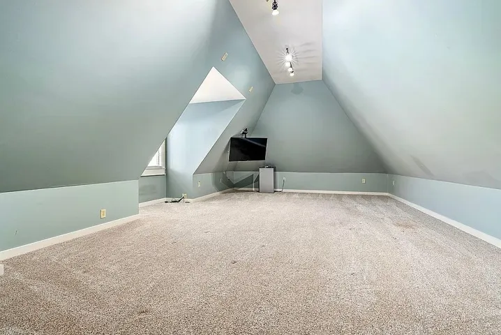 A spacious attic offering versatile living space with sloped walls and warm lighting.