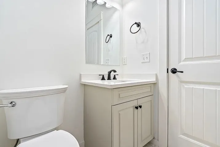 A well-appointed half bath features a vanity with ample counter space and a modern toilet.