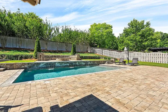 A private backyard oasis features a glistening pool with cascading water features and extensive paver patio.