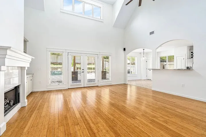 Natural light floods this generously proportioned living space, highlighting the rich hardwood floors and architectural arches.
