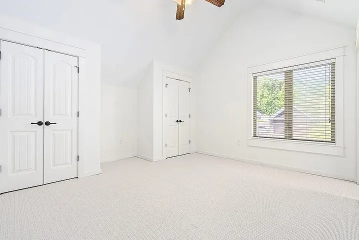 A quiet bedroom featuring vaulted ceilings, plush carpeting, and generous closet space.