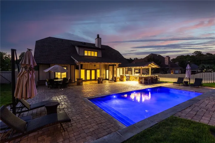 An inviting backyard oasis features an illuminated pool and a fully equipped outdoor kitchen for memorable entertaining.
