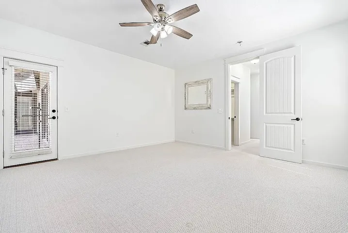A tranquil bedroom with soft carpet flooring and a glass-paned door leading to the outdoors.