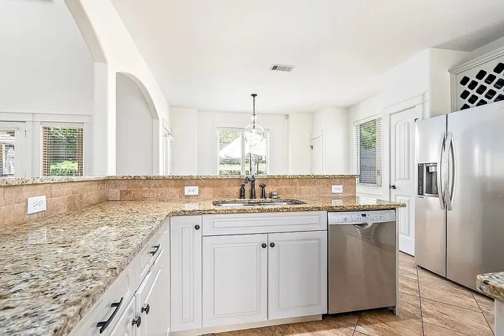 Granite counters and stainless steel appliances adorn this well-appointed kitchen with an inviting open layout.