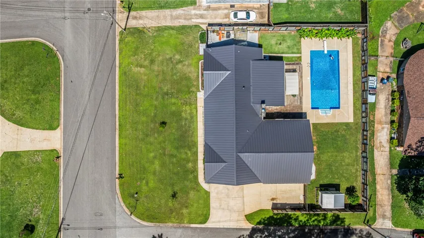 An aerial perspective reveals the property's generous yard, inground pool, and ample concrete driveway.