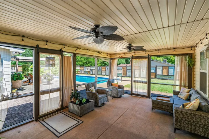 A screened porch with dual ceiling fans offers views of the sparkling pool and landscaped yard.
