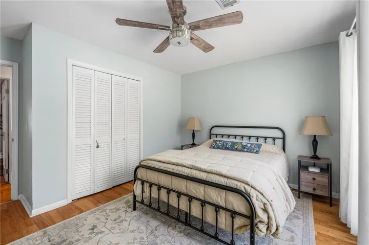 Hardwood flooring and a ceiling fan enhance this cozy bedroom, creating a comfortable retreat.